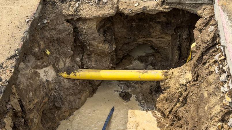 A yellow water pipe in a trench at a construction site.