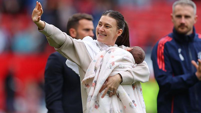 Hannah Blundell of Manchester City takes part in a lap of honour holding her newborn child 