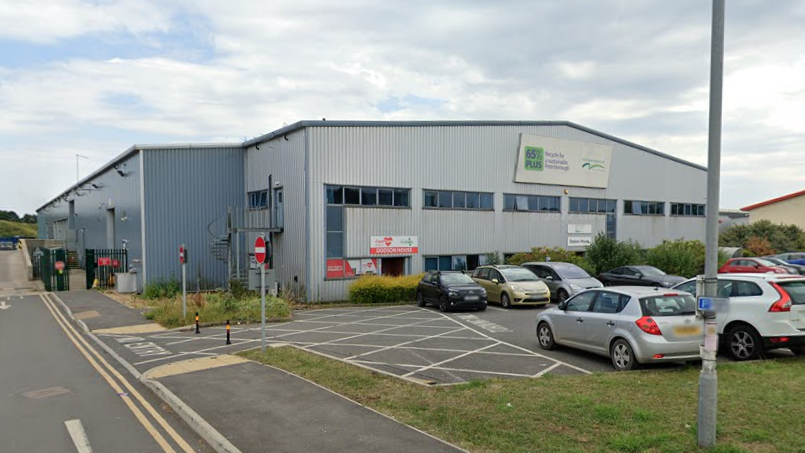 The outside of the Household Waste Recycling Centre in Fengate in Peterborough, which is a big steel building. There is a car park outside the front.