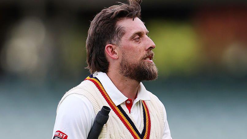 Jake Lehmann pictured walking with a bat while playing for South Australia