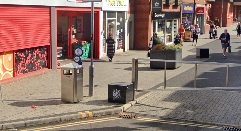 A litter bin in Bell Street in Wigston with shops in the background