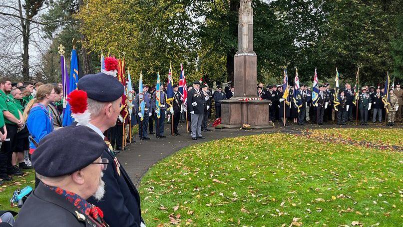 People are lined up around the war memorial with colourful flags for the parade and service in Bedworth.