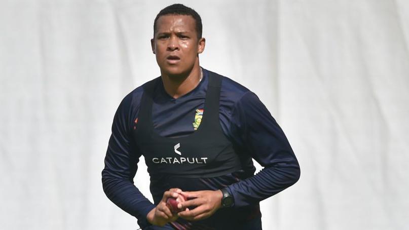 Glenton Stuurman gets ready to bowl, wearing a dark navy blue training kit