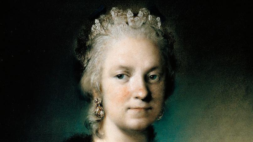 A portrait of a woman. She has grey hair and is wearing earrings.
