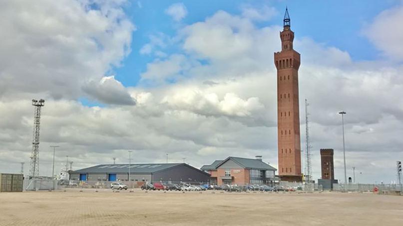 A long view of the Grimsby Dock Tower across an open piece of land in the docks