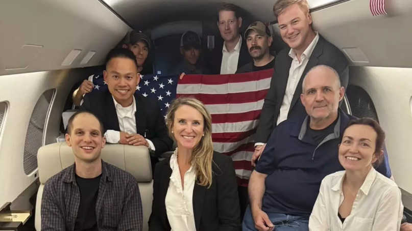 This image released by the White House shows Evan Gershkovich, left, Alsu Kurmasheva, right, and Paul Whelan, second from right, and others aboard a plane Thursday after their release from Russian captivity