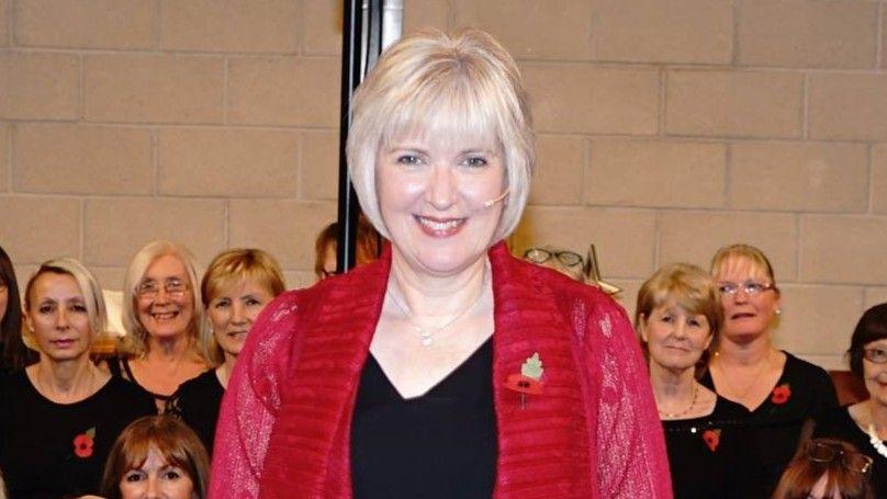 Pauline Daglish with members of the choir standing around her.