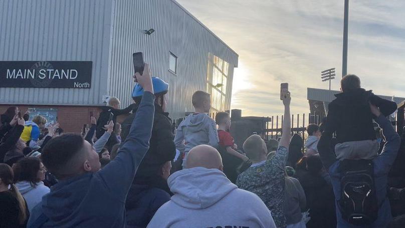 Crowds holding phones up outside St Mirren FC with some children on the shoulders of parents 