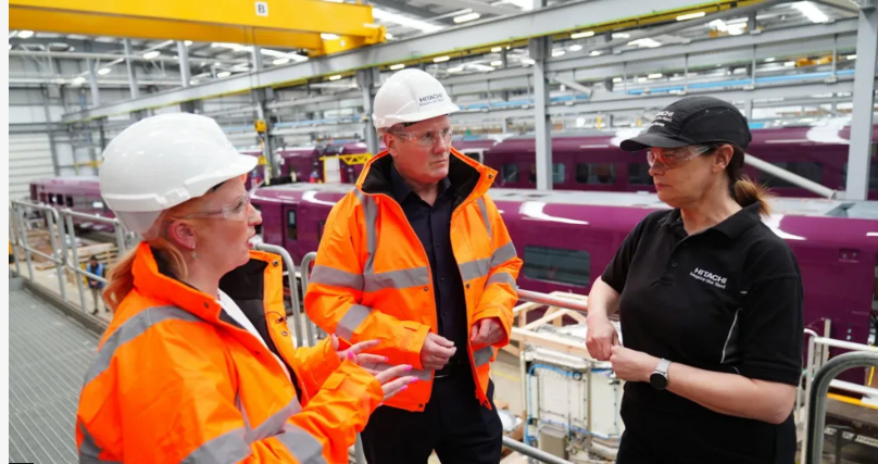 Sir Keir Starmer on a visit to Hitachi, wearing a hi-vis orange jacket.