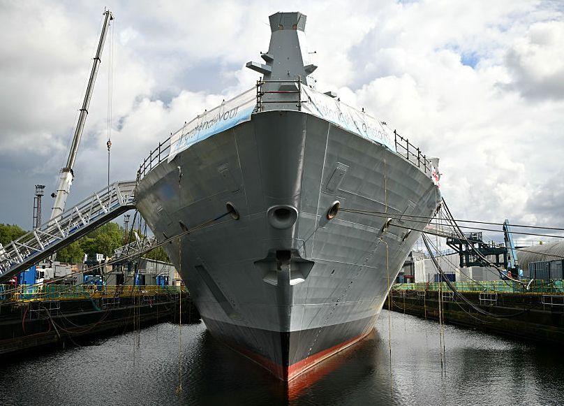 A large ship, viewed bow on, in a fitting out dock