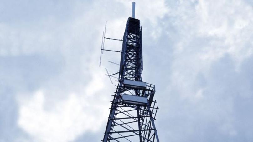 Looking upwards at the criss-crossed metal structure of a TV transmitter