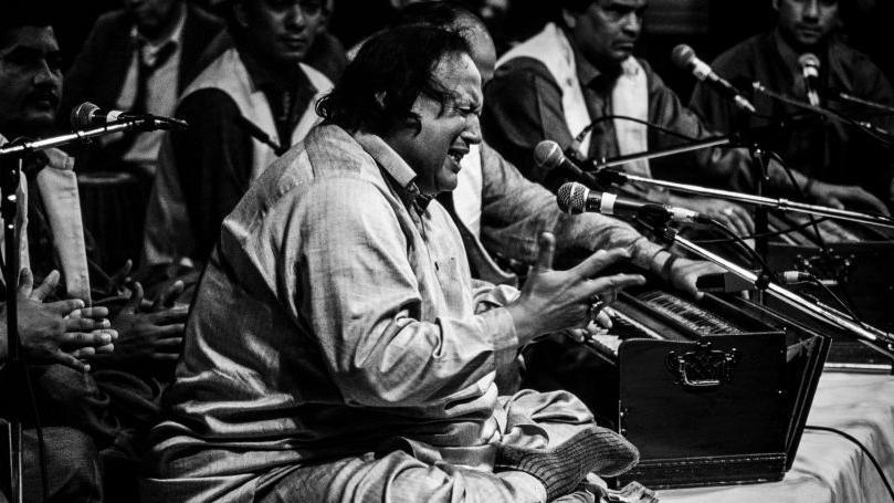 Nusrat Fateh Ali Khan on stage surrounded by microphones