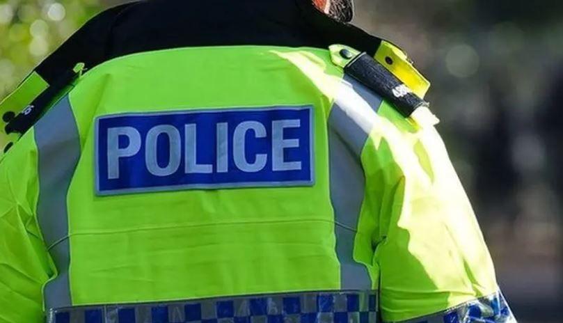 A picture of a police officer from the back. Their head is out of shot and they are wearing a bright jacket with the word POLICE on it.