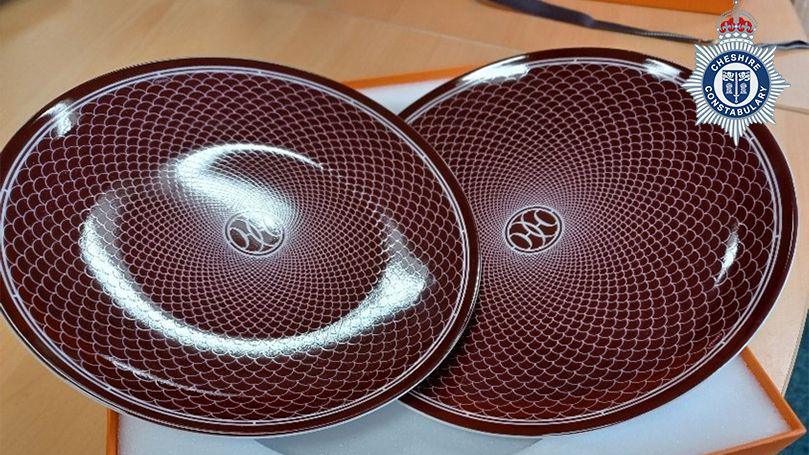 A pair of burgundy Hermes plates with a white fish scale pattern printed on them
