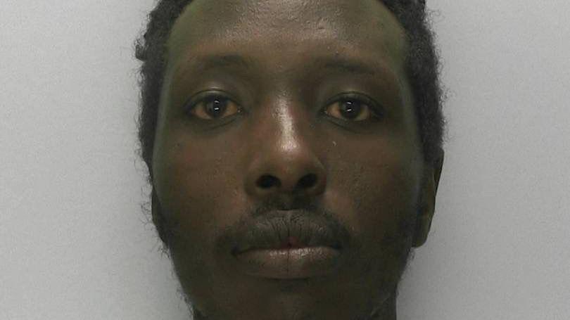 A bearded man looking at the camera in a police mugshot