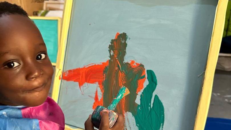 Smiling toddler painting on a canvas