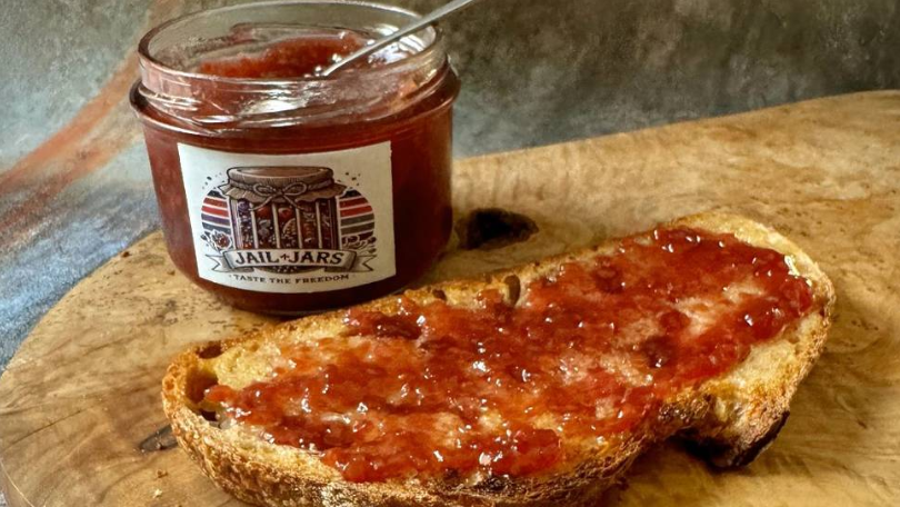 A table with a slice of toast and jam, and a jam jar labelled "Jail Jars - Taste the Freedom"