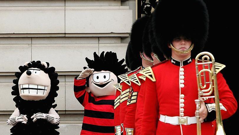 mascots of Dennis the menace and Gnasher with the royal guard outside Buckingham palace