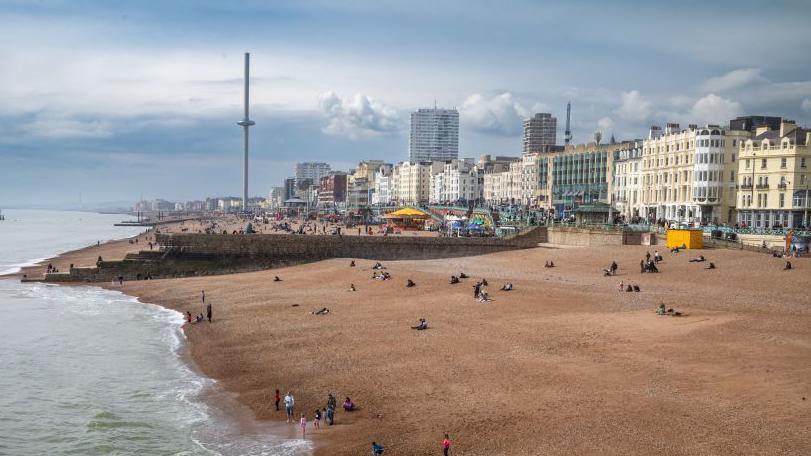 A view over Brighton seafront. There is a pebbled beach and buildings in the background.