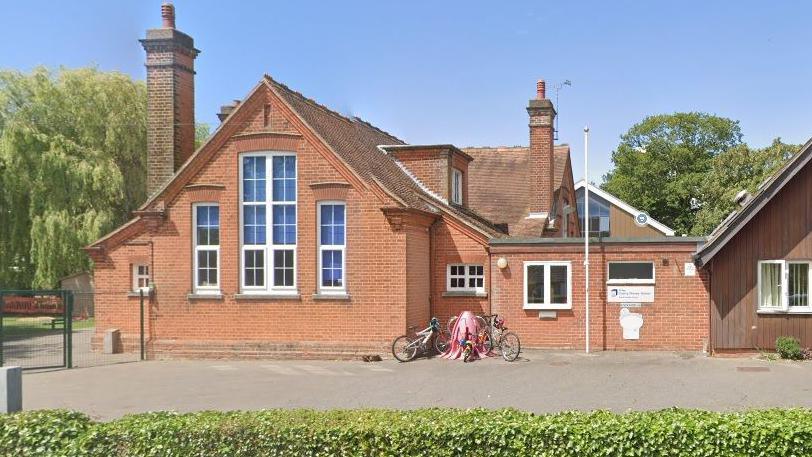 Otley Primary school exterior. Victorian style building with large oblong windows. Bikes are parked against a wall. 