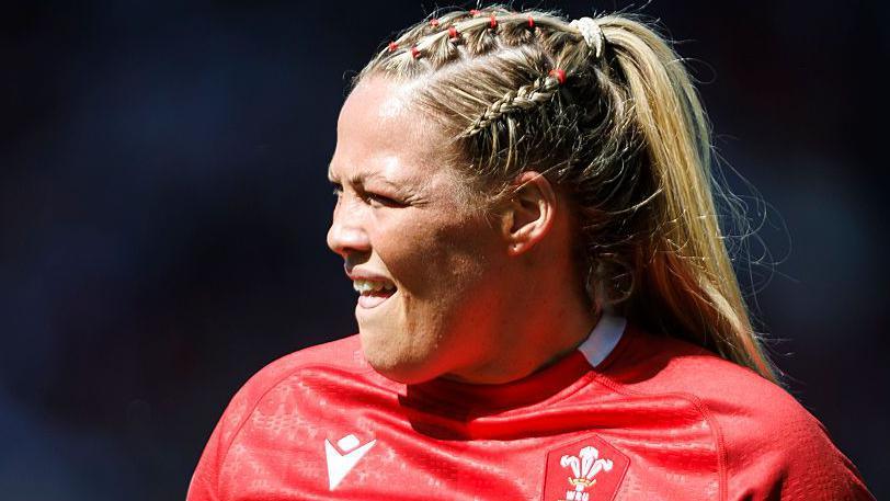 Kelsey Jones playing for Wales on a very sunny day as she squints looking towards the sunlight
