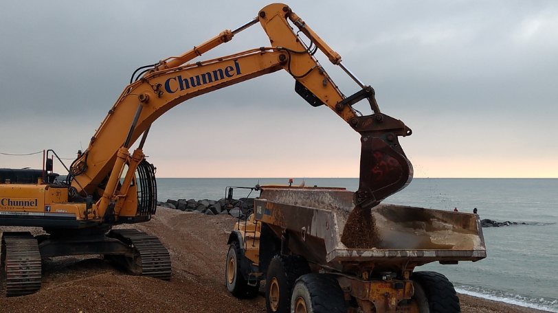 A digger scooping shingle into a truck