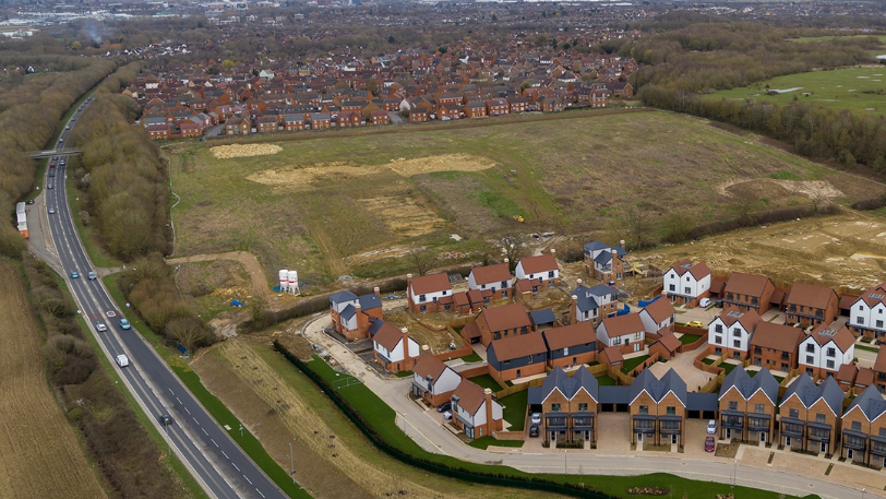 Aerial view from 2023 of some of the new houses in Chilmington Green. Dozens of houses can be seen. 