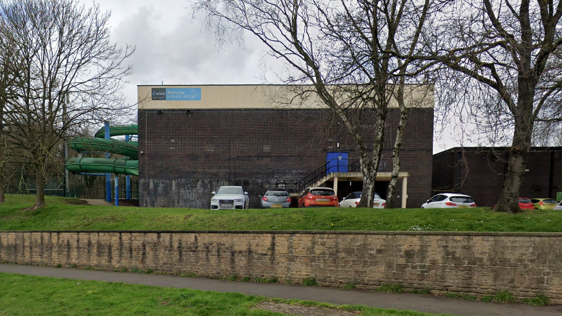 A Streetview image of the current leisure centre, an aging brown brick rectangular building with no visible windows.