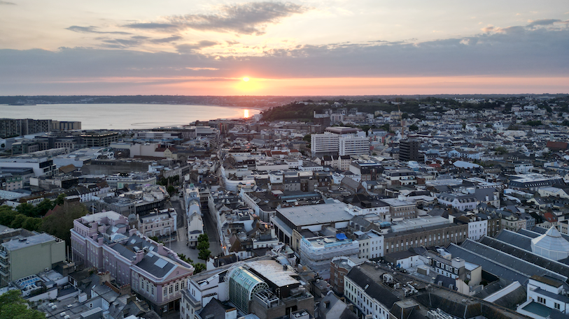 An aerial view of sunset over St Helier, with the ocean in the background.
