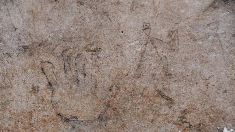 A hand and gladiators fighting drawn in stone