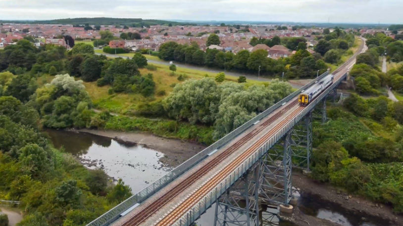 A two-carriage train crosses a railway viaduct.