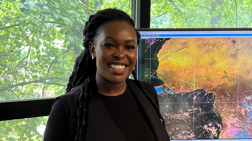 Sarah Kimani, of the Kenyan Meteorological Department, stands in front of a meteorological map.