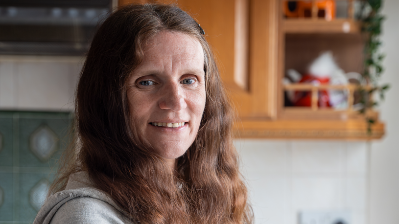 Wendy Wheat, 53, standing in front of a window, with red, curly hair.