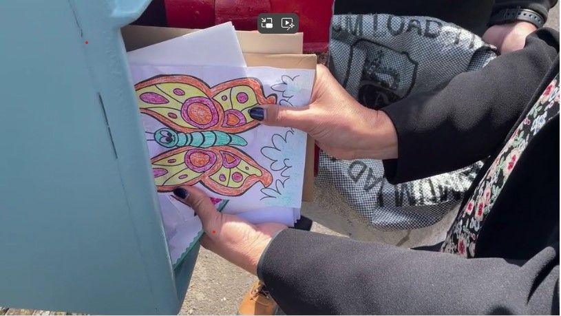 A woman removed a sheaf of letters, cards and drawings from a blue postbox