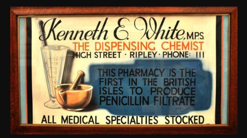 An old fashioned sign reading Kenneth E White MP, the dispensing chemist, high street, Riple, Phone III. This pharmacy is the first in the British Isles to produce penicillin filtrate. All medical specialities stocked.