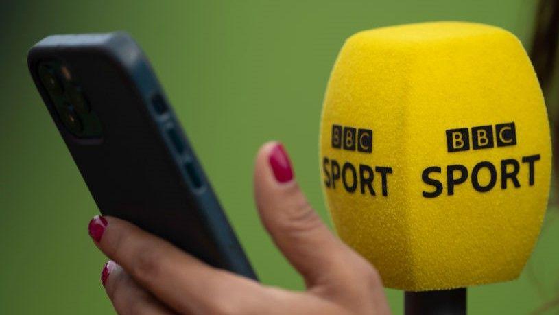 Reporter checking the BBC Sport app on a mobile phone