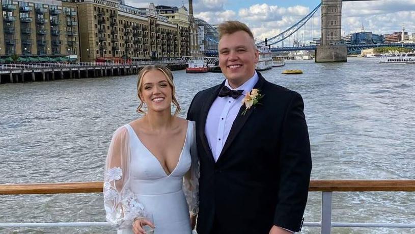 Hannah and Max smiling on their wedding day in front of Tower Bridge