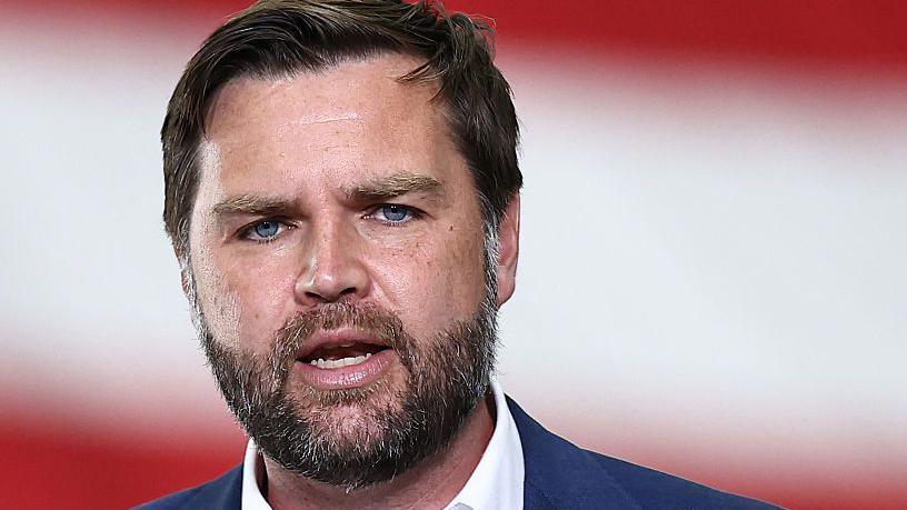 JD Vance, a man with a beard, dark hair and blue eyes