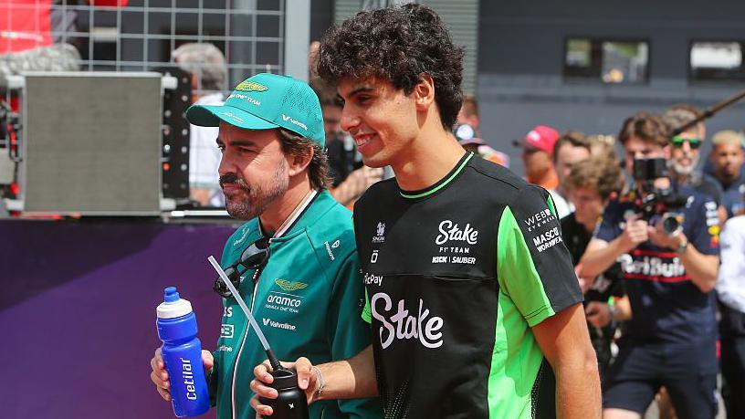 Gabriel Bortoleto and Fernando Alonso walk side-by-side at the Hungarian Grand Prix