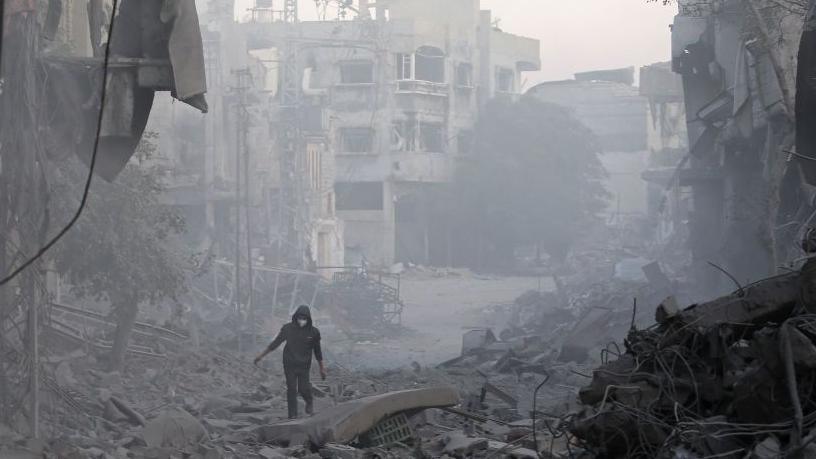 A man walks through the rubble of buildings destroyed in Israeli air strikes at Bureij refugee camp, in central Gaza (12 January 2025)