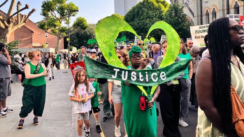 Grenfell campaigners carrying placards and signs march through west London