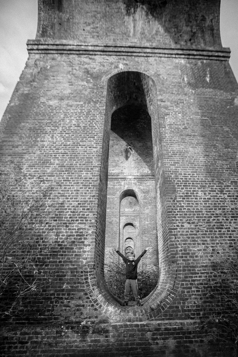 A child stands in an arch - part of the supporting structure of a viaduct in Essex