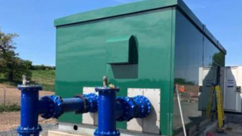 A large green metal container with two large blue metal taps coming out of the side.