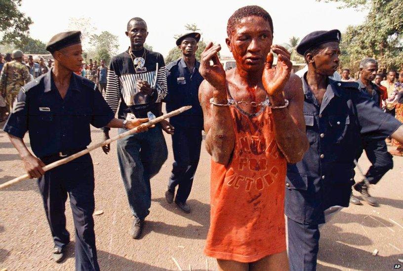 A man accused of collaborating with the military junta in Sierra Leone is taken by police to the West African peace keeping force's headquarters after he was attacked by civilians in the town of Makeni March 7, 1998.