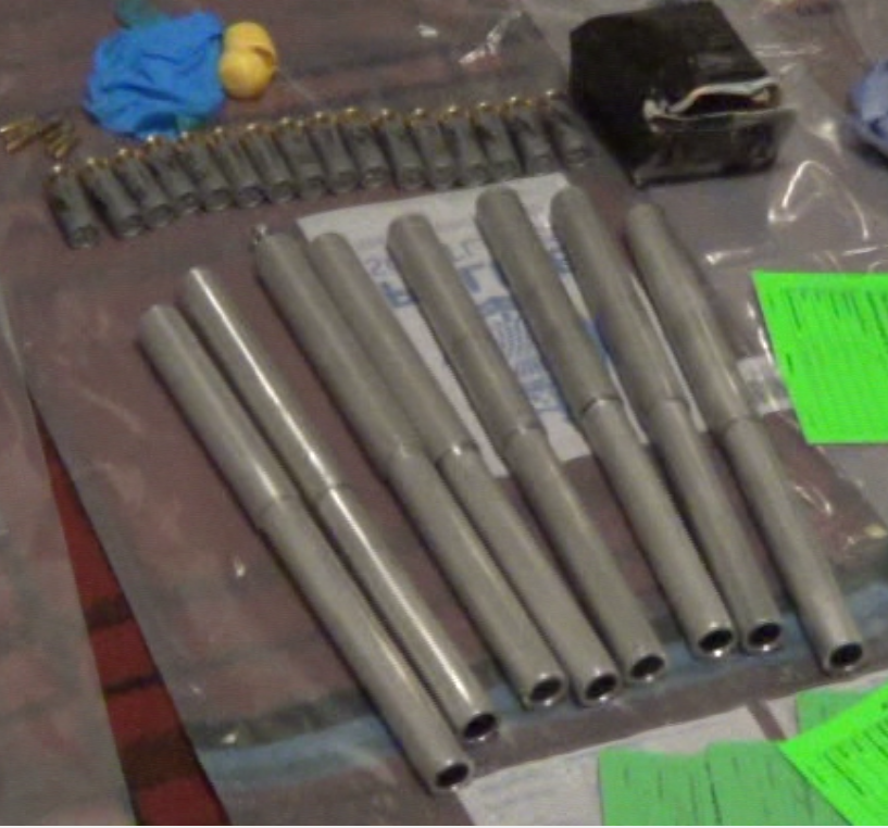 Metal poles and bullet cartridges laid out on a table with blue examination gloves