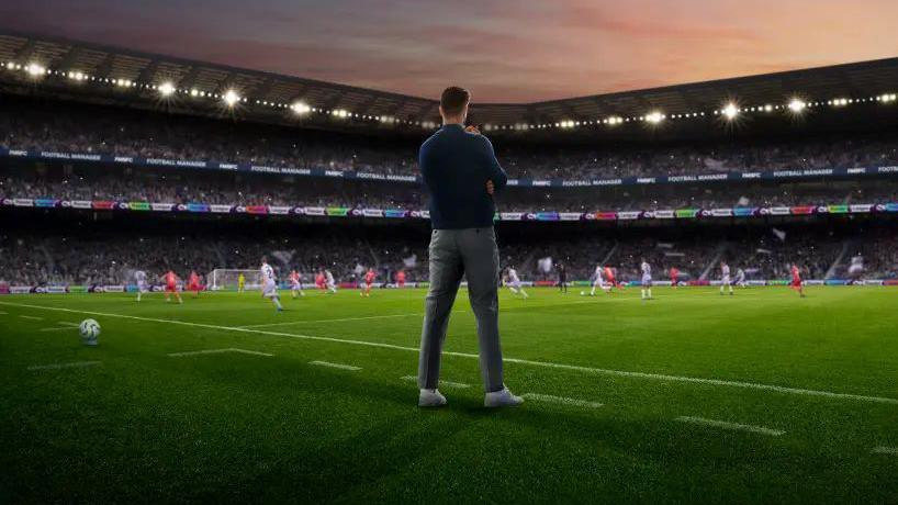 A still from the Football Manager game which shows a manager on the side of the pitch, with green coloured grass and white lines.