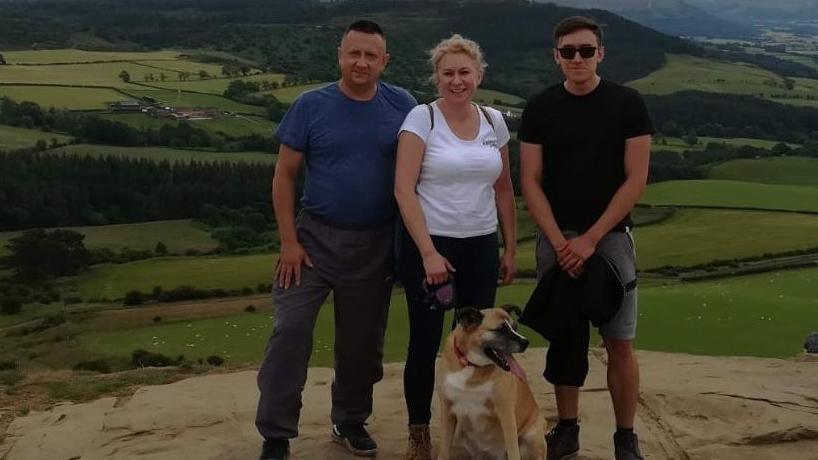 Kamil Grygieniec poses for a photo with his mum, dad and a dog.