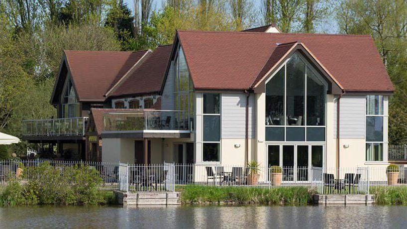 The exterior of the San Giovanni restaurant which is next to a lake. 