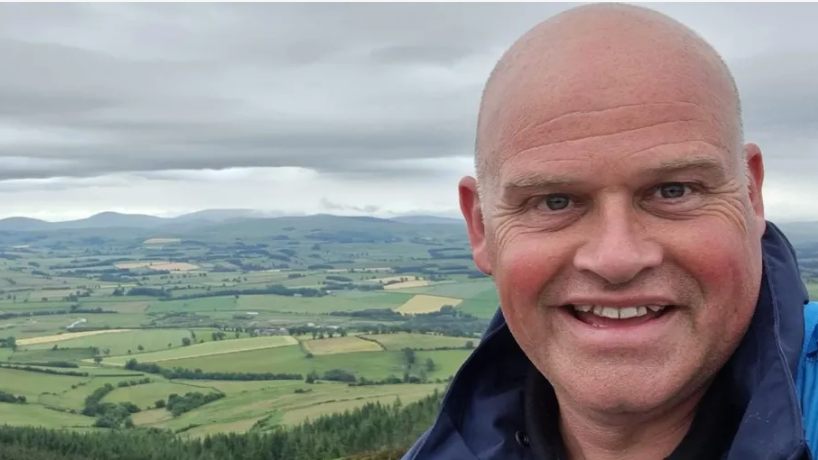 Matt Hayward on a hill overlooking green fields with hills in the distance