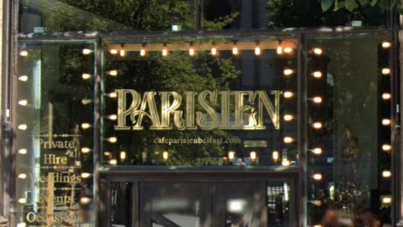 The entrance to Parisien, with the restaurant name in large gold letters. The name is also surrounded by lights.